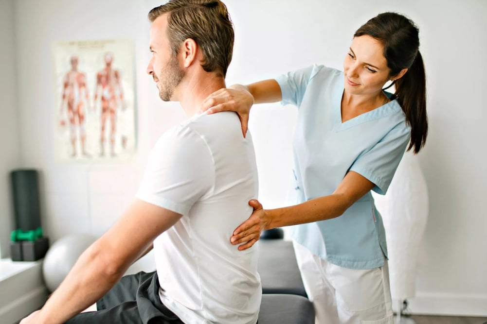 fisio tocando la espalda de un paciente